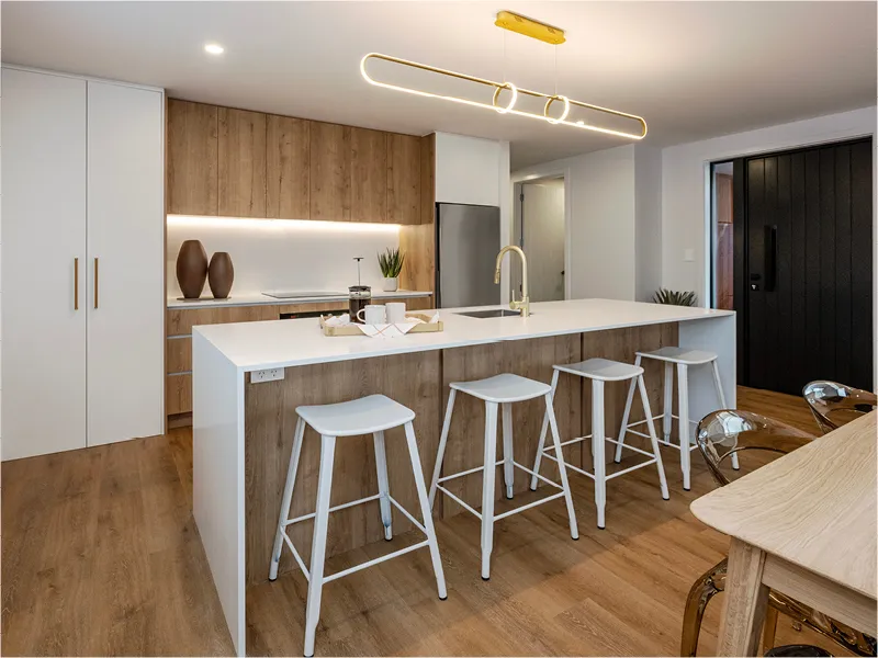 Street view of the Napier lottery prize home showcasing gable-roof architecture, timber cladding, double garage, and landscaped front lawn at dusk.