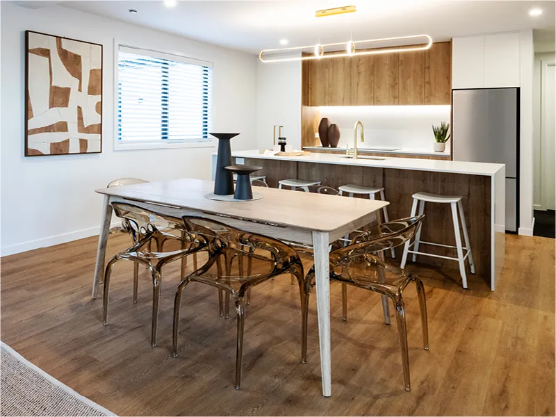 Galley-style kitchen in the Napier lottery home with woodgrain cabinetry, white stone benchtops, island sink, and stainless-steel appliances.