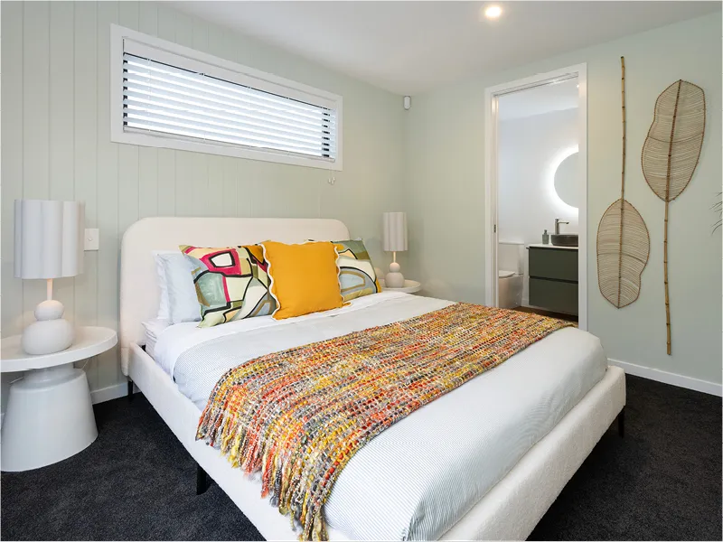 Children’s bedroom in the Napier home with pink upholstered bed, checkered bedding and rug, and minimalist decor.