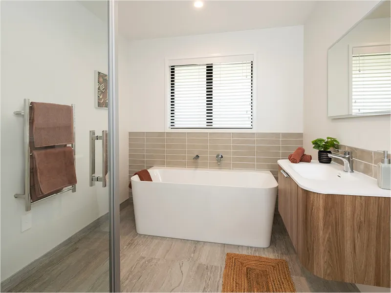 Modern bathroom with freestanding bathtub, timber vanity, tiled splashback, window blinds and grey wood-look flooring