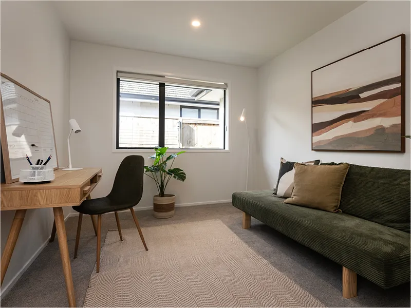 Modern home office with timber desk and chair, green daybed sofa, indoor plant and window light.