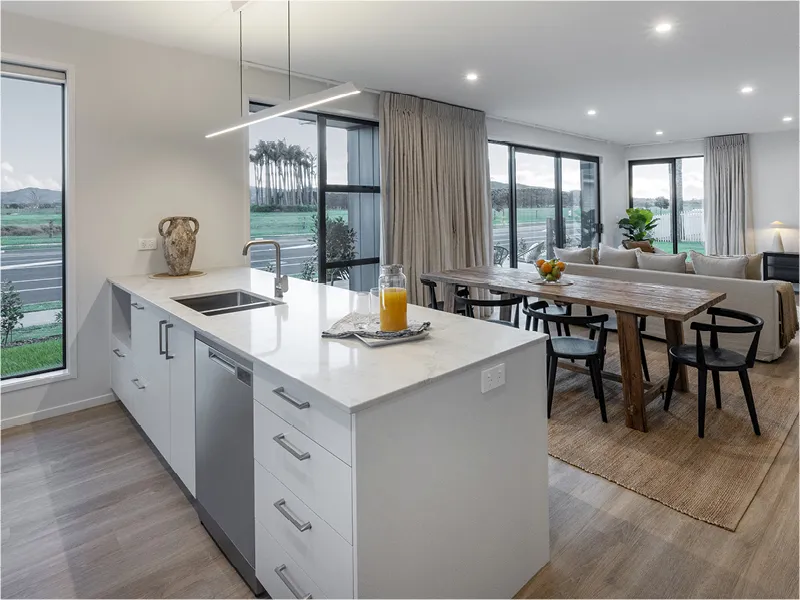 Stylish Papamoa living room with neutral sofas, round rug, and large sliding glass doors to outdoor deck.