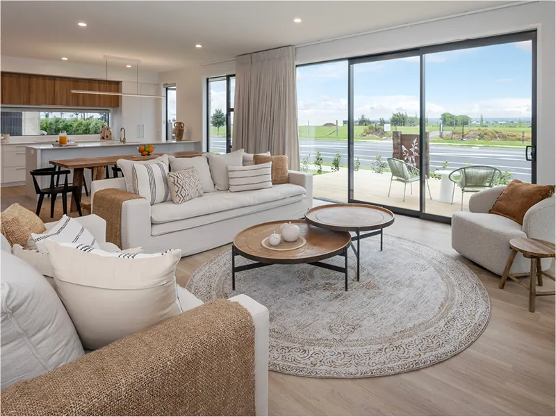 Open-plan living room in Papamoa with neutral sofas, round coffee tables and large sliding doors to patio.