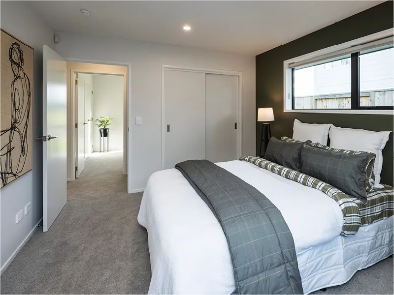 Contemporary bedroom with grey feature wall, white bedding and plaid accents, built-in sliding wardrobe and window