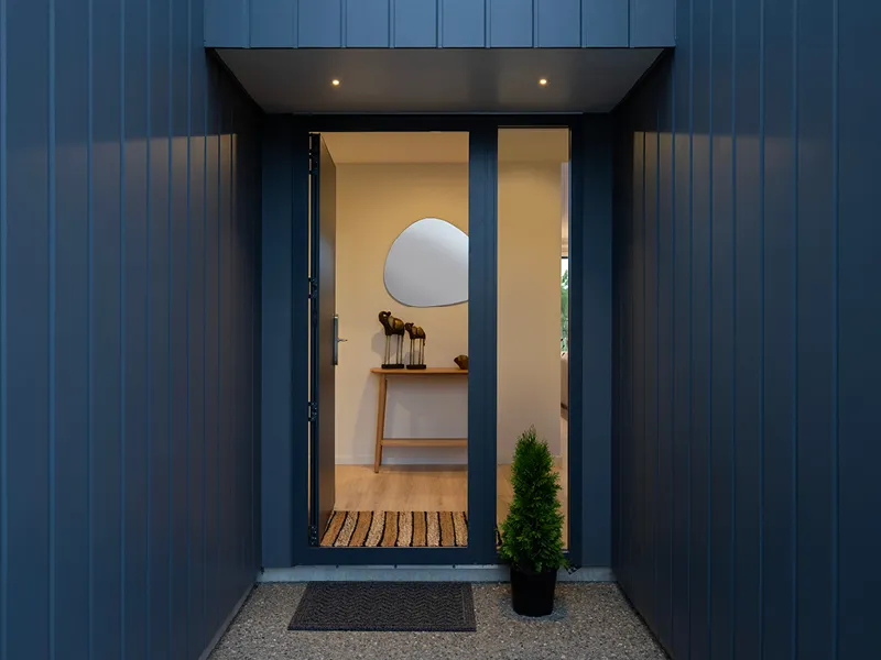 Covered front entrance of the Heart Foundation Home Lottery 162 three-bedroom house in Richmond, Nelson with dark cladding and welcoming foyer décor