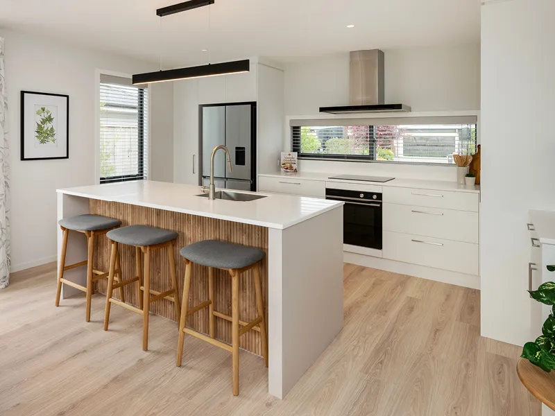 Modern kitchen in the Heart Foundation Home Lottery 162 three-bedroom house in Richmond, Nelson with island bench, bar stools and stainless-steel appliances.