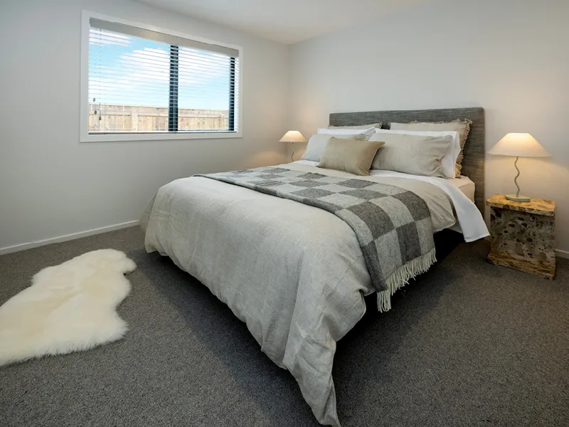 Guest bedroom in the Heart Foundation Home Lottery 162 three-bedroom house in Richmond, Nelson with queen bed, soft neutral bedding and bedside lamps.