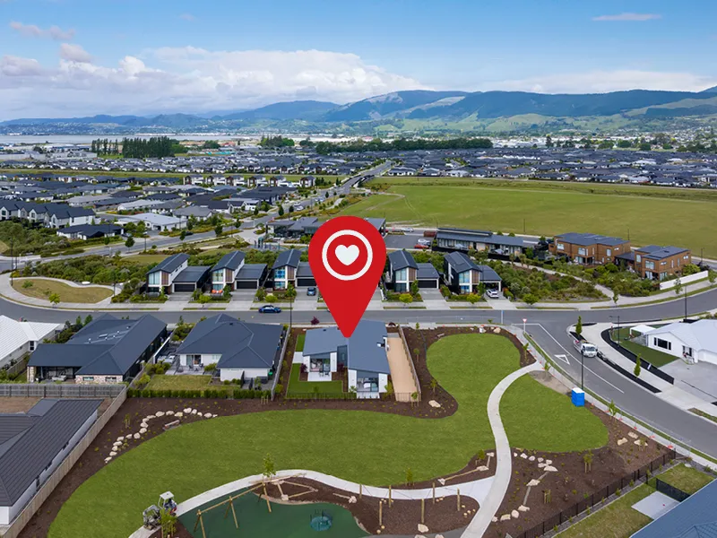 Aerial view showing the Heart Foundation Home Lottery 162 three-bedroom house in Richmond, Nelson highlighted near park, playground and mountain backdrop.