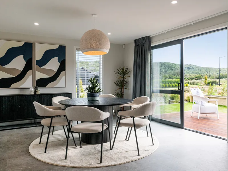 Stylish Kinloch dining area with round table, upholstered chairs and sliding doors opening to outdoor deck and garden.