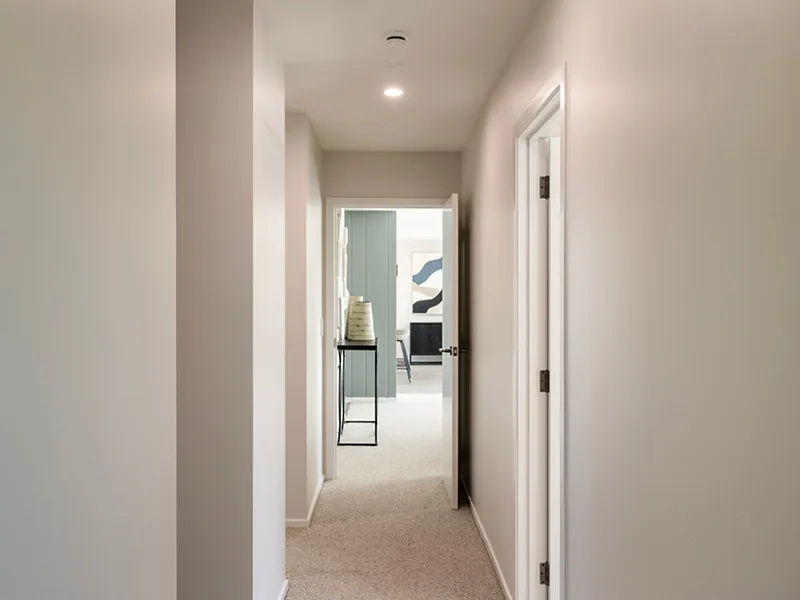 Light hallway in Kinloch home leading to living area, with neutral walls and carpet flooring.