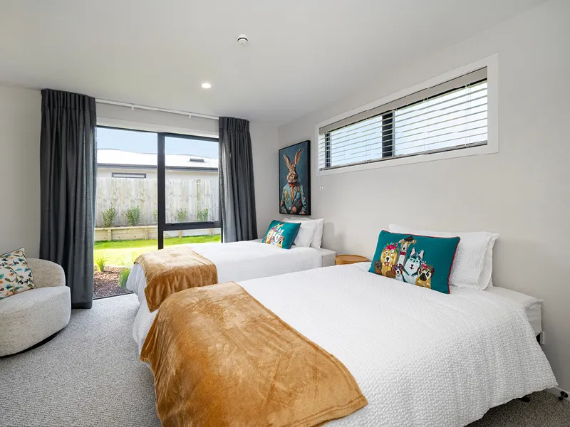 Bright Kinloch twin bedroom with two beds, colourful cushions and sliding doors to garden.