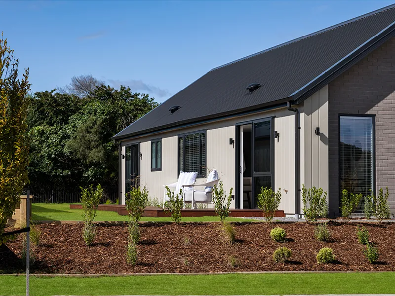Rear exterior of modern Kinloch home with landscaped garden, deck and outdoor seating.