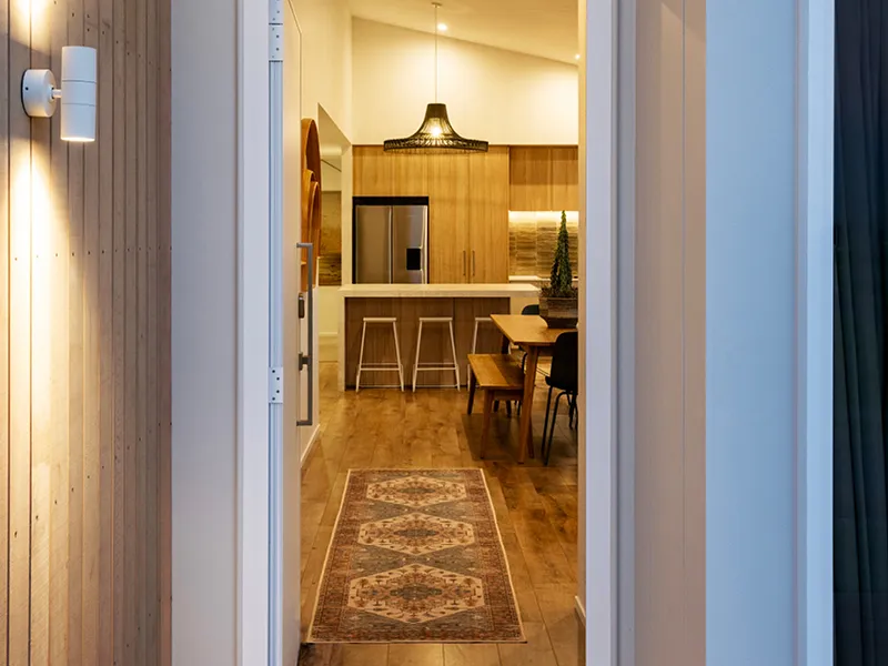 Entryway view through to the timber kitchen, dining area and woven pendant light in the Omokoroa Jennian home.