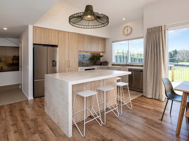 Modern kitchen with white stone island bench, oak cabinetry and woven pendant light in the Heart Foundation lottery house.
