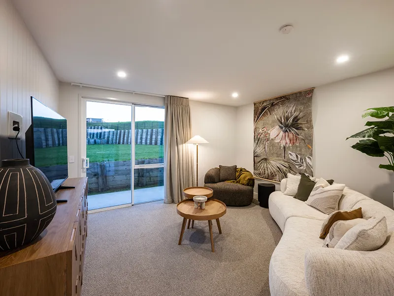 Second living area with white sectional sofa, floral wall tapestry and sliding doors to the backyard in the Heart Foundation Home Lottery No. 165 Ōmokoroa house.