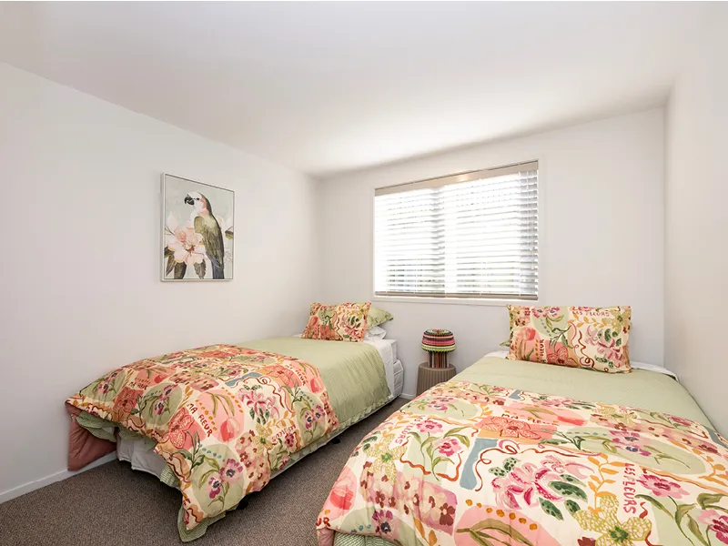 Third bedroom with twin beds, floral bedding and bird artwork in the Heart Foundation Home Lottery No. 165 Ōmokoroa house.
