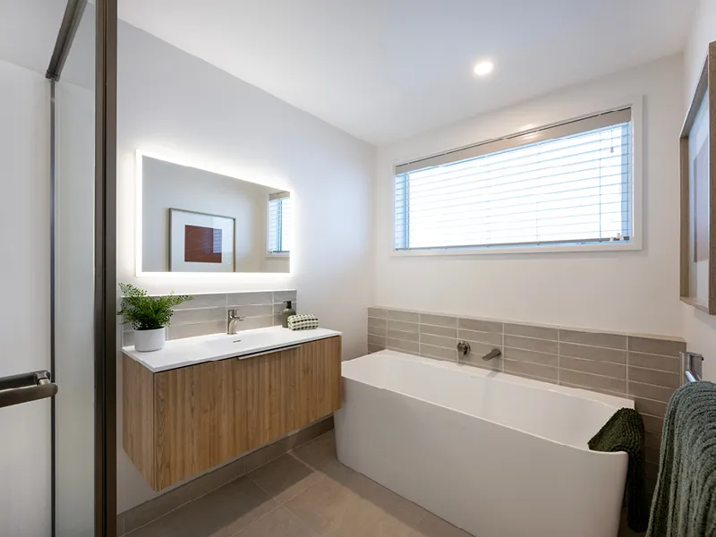 Family bathroom with freestanding bathtub, backlit mirror and walk-in glass shower in the Heart Foundation Home Lottery No. 165 Ōmokoroa house.