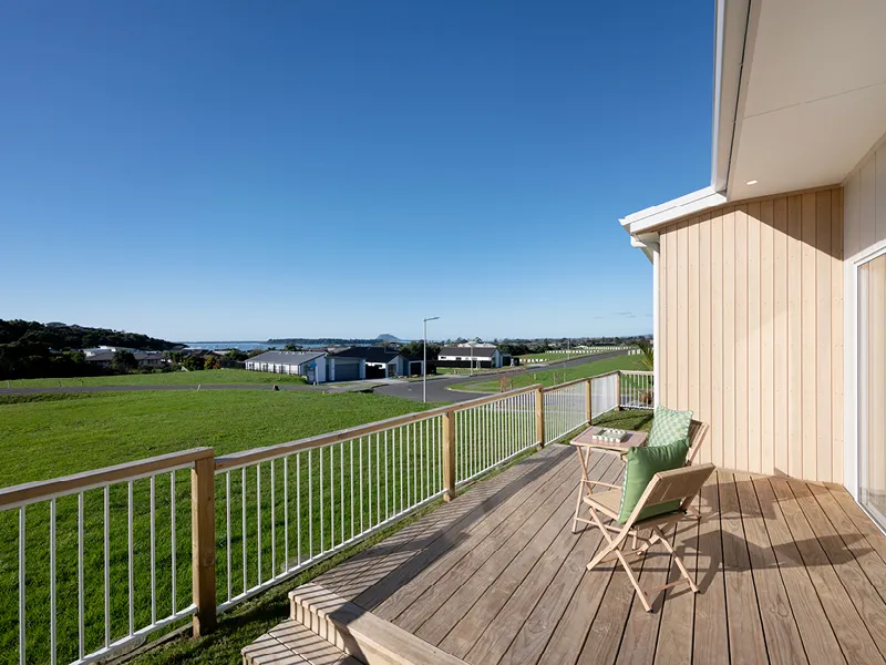 Timber deck with outdoor chairs overlooking Ōmokoroa harbour and rural paddocks in the Heart Foundation Home Lottery No. 165 house.