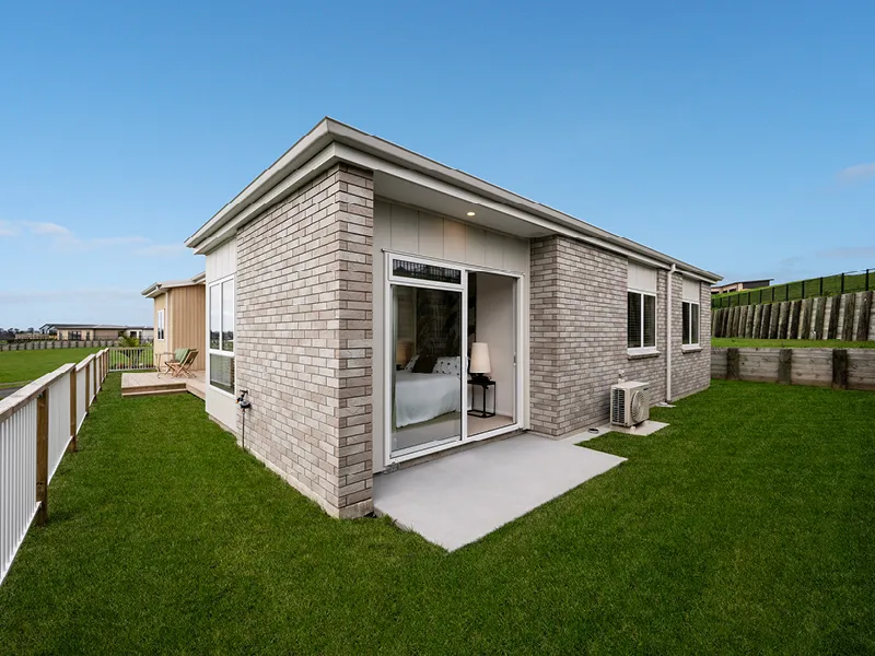 Exterior of the brick-clad master suite wing with private patio and heat pump unit in the Heart Foundation Home Lottery No. 165 Ōmokoroa house.