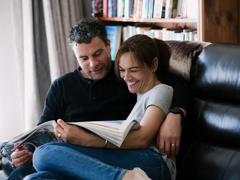 Couple relaxing at home together, smiling while reading — supporting heart health and wellbeing.