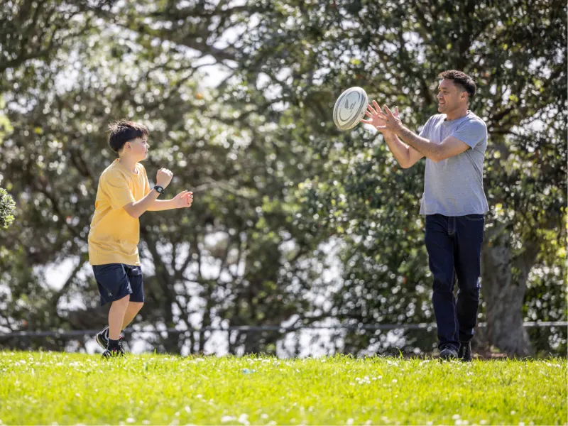Adult and child playing frisbee together in a sunny park, enjoying active outdoor time and healthy heart‑friendly exercise.