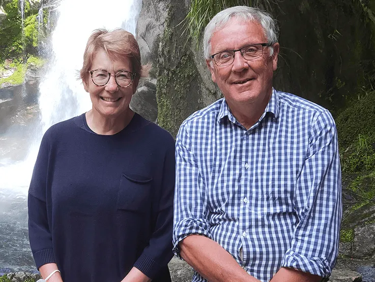 Photo of Phil Elvidge and his wife sitting in front of a waterfall. Phil was born with a congenital heart condition and has had a number of heart surgeries.