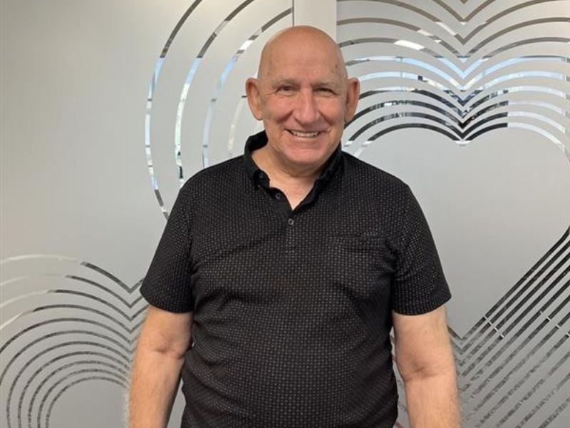 Man in black shirt standing in front of decorative frosted glass wall with heart pattern