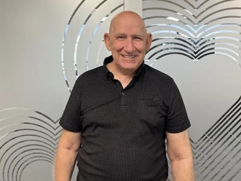 Man in black shirt standing in front of decorative frosted glass wall with heart pattern