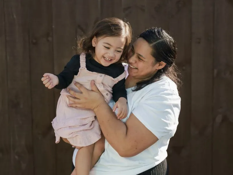 Family standing together outside brick home, showing whānau support for rheumatic fever and rheumatic heart disease care in New Zealand.