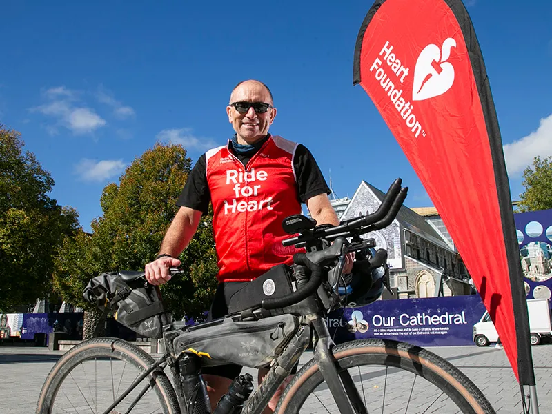 Professor Rob Doughty with his bicycle next to a Heart Foundation banner