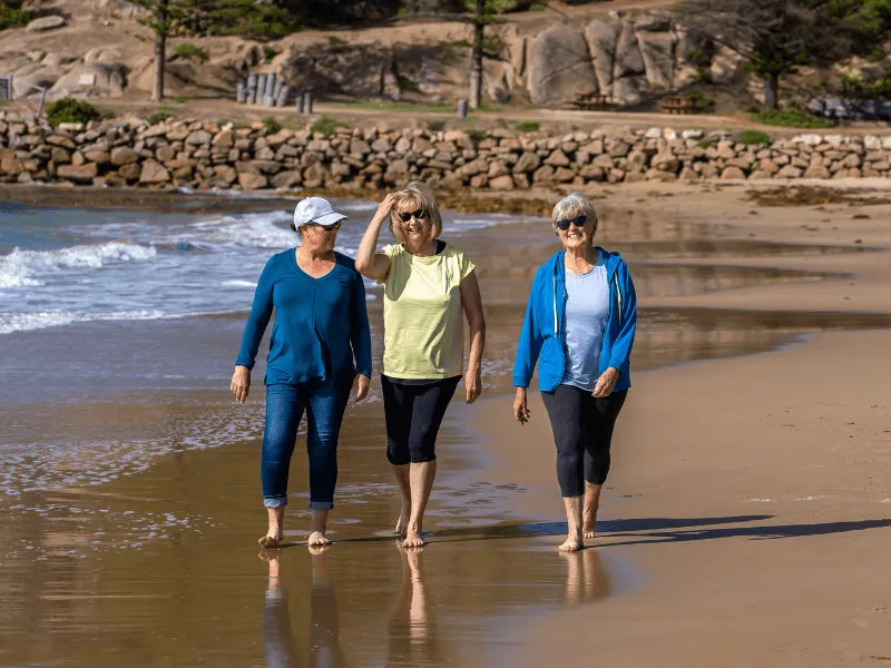 An image of 3 older women walking on the beach