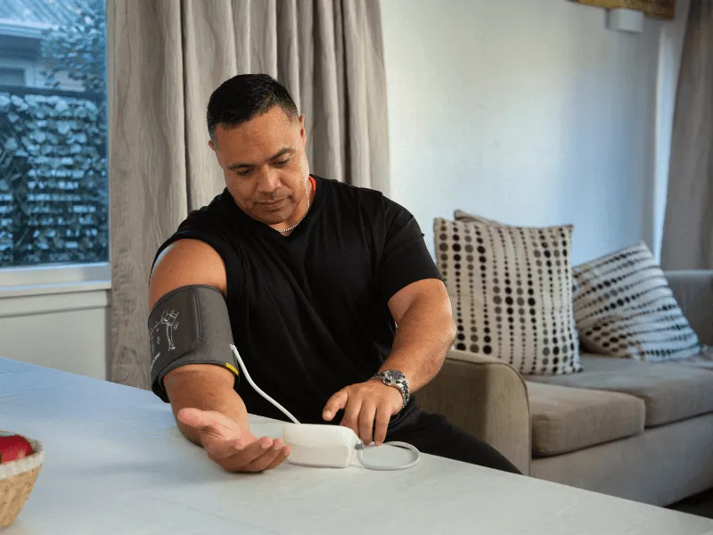 Image of man checking his blood pressure using a blood pressure monitor.