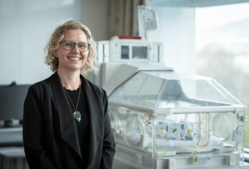 Specialist neonatal paediatrician Dr Sarah Harris standing in front of an incubator.