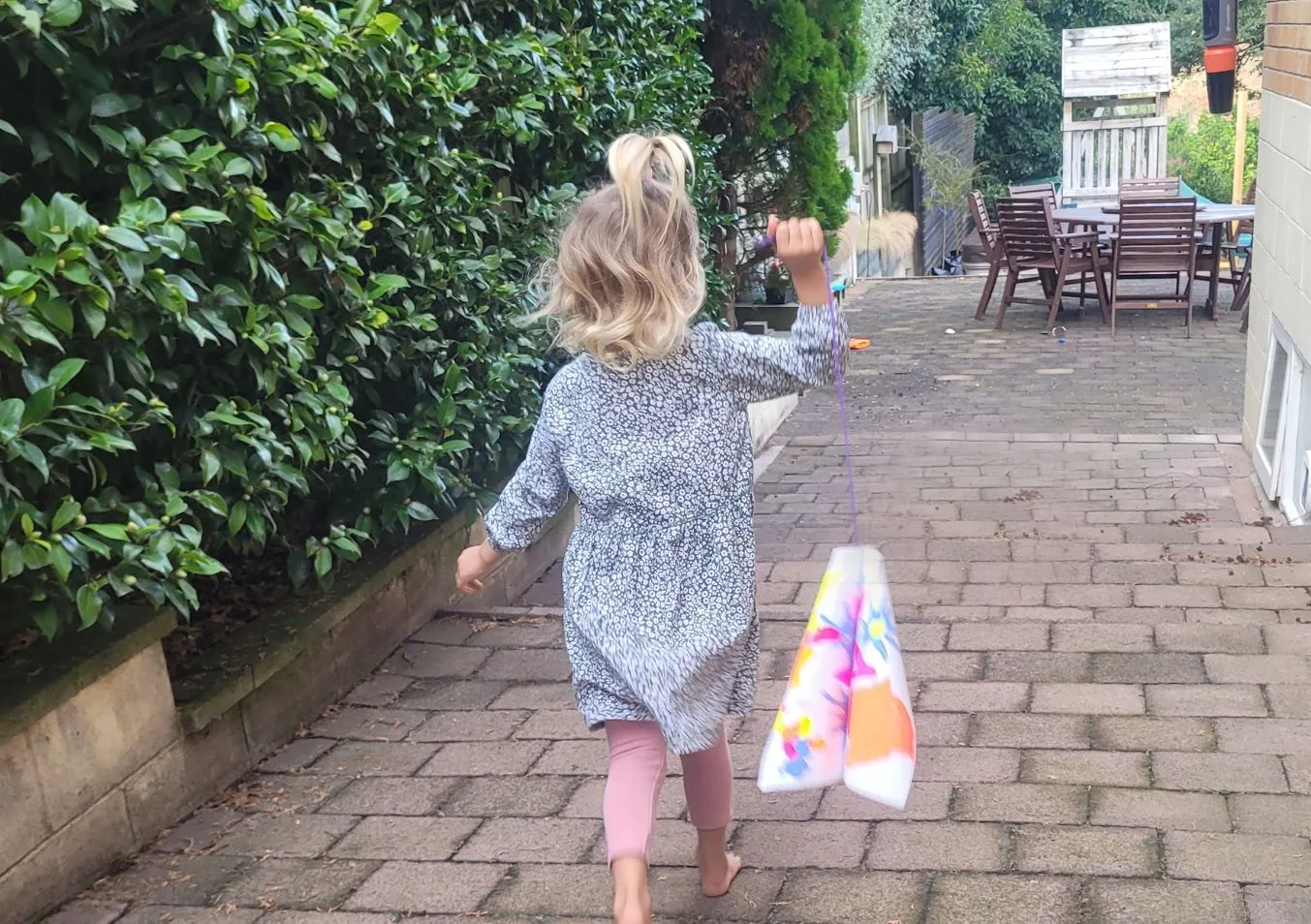 A girl in her backyard, with a self-made kite
